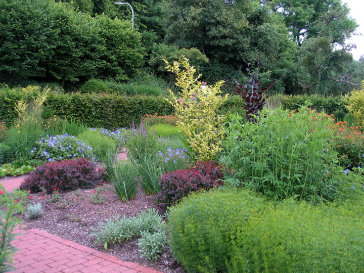 Schlossgarten Dagstuhl. Ein kleiner Garten inmitten eines alten Baumbestandes und bepflanzten Blumenbeeten.